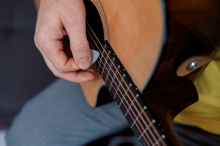 Guitarist on acoustic guitar playing melody. Close up musician instrument with pick in handの写真素材