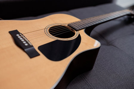 Beautiful six-string acoustic guitar, wood body, on sofa in studioの写真素材
