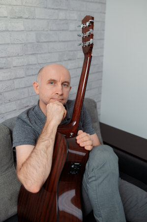 man guitarist playing guitar at home. Relaxing and sitting on sofaの写真素材