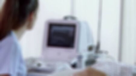 Blurry view of Gynecologist doctor prepares an ultrasound machine for the diagnosis of the patient. Applies gel to a transvaginal ultrasound scanner. Women`s Health Conceptの写真素材