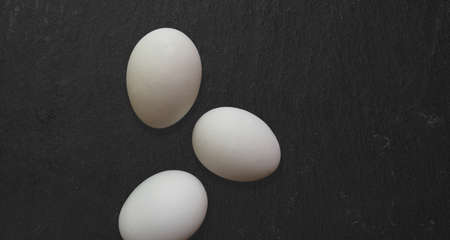 Top up view isolated fresh chicken eggs isolated on dark table. added copy space for text.の写真素材