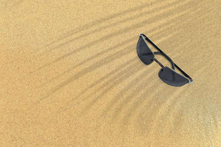 Top up view of black sunglasses on sand beach. vacation concept background.の写真素材