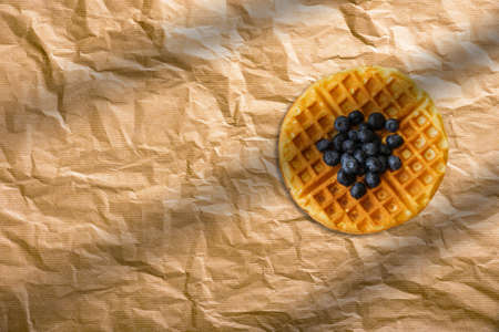 Fresh homemade waffle with blueberry on baking paper. French bakery concept