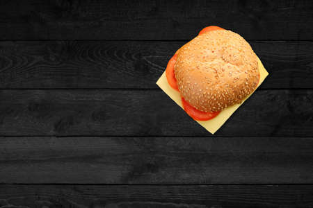 Close up view of hamburger with cheese isolated on black wooden table.の写真素材