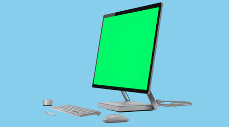 A computer setup with a blank green screen, keyboard, mouse, and a small device.の写真素材