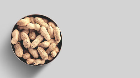 Close up photo of top view peanuts added on ceramic bowl, raw peanuts in the nutshells isolated on...