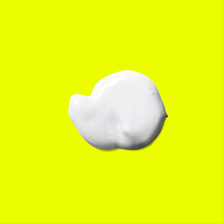 Close up view of white paint splash isolated on yellow background.の写真素材