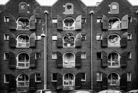 AMSTERDAM, NETHERLANDS. JUNE 06, 2021. Beautiful facades of the old dutch buildings. House with a names of the Citiyes on the balcony. Black and white photography.のeditorial素材