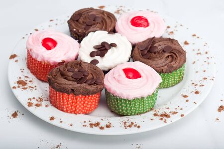 Colorful, delicious cupcakes on a white plate decorated with cinnamon sprinklesの写真素材