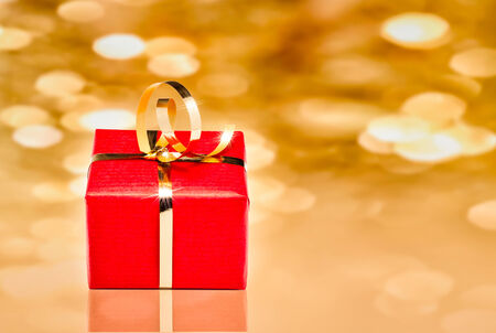 red and gold gift box with out of focus lights on a golden backgroundの写真素材