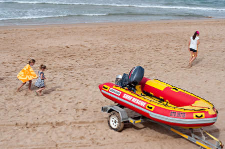 DURBAN, SOUTH AFRICA - JULY 09, 2016: Children playing on the beach near a surf rescue boat in Umhlanga Rocksのeditorial素材