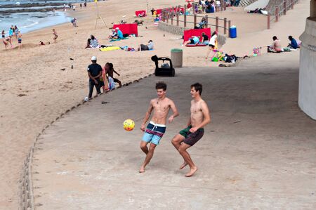 DURBAN, SOUTH AFRICA - JULY 09, 2016: Boys paying beach soccer near the Millennium Pier and lighthouse in Umhlanga Rocksのeditorial素材