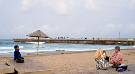 DURBAN, SOUTH AFRICA - AUGUST 17, 2015: People sitting near the pier at North Beach on the Golden Mile promenade.のeditorial素材