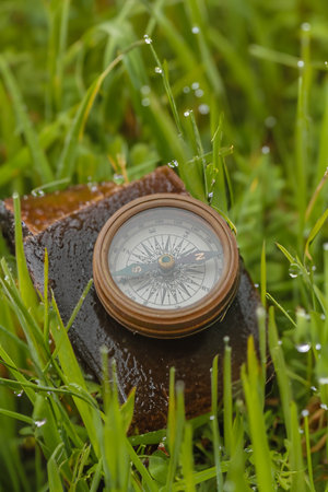 Old brass compass on a worn leather case and grassの素材