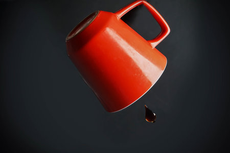 Red cup with morning coffee with one drop against a black backgroundの素材