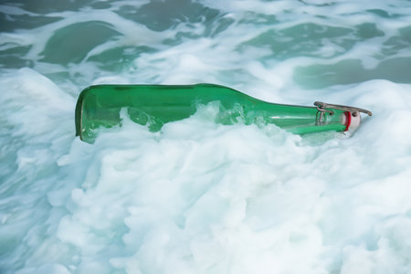 Vintage glass bottle washed up on shore depicting an enviromental hazardの素材