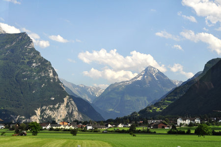 Swiss alps mountain rage highlands showcasing scenic pine trees, lush grass fields and steep rocky cliff, taken from canton of Zermatt, on a summer holiday.の写真素材