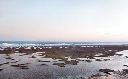 Catching scenic sunset sky at Melasti Beach, Uluwatu, Nusa Dua, Bali, Indonesia, with nice waves and low tides, along with summer breeze for a perfect holiday, vacation, and travelの写真素材