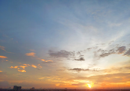 Magnificent view of sunset sky with beautiful combination of blue sky colours, ember sun lights, and several floating clouds above the city skyline.の写真素材