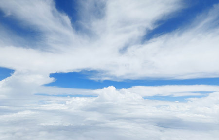 Aerial photography of clear blue sky with white clouds seen from airplane window.