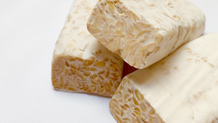 Close up sliced photo of Tempe or Tempeh, showing the Rhizopus Oligosporus, a fungi species that's...