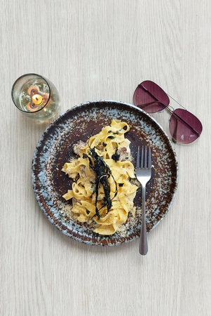 Truffle Cream Mushroom Fettucine on a grungy texture plate served on a white wooden rustic table, with sunglasses for a perfect picnic brunch set.の写真素材