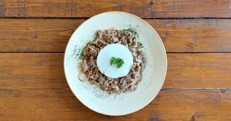 Shredded beef with champignon mushrom and creamy cheese sauce with white gluttened-free rice, served on a wooden rustic table.の写真素材