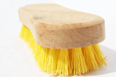 Scrub brush with polyester yellow bristles and wood handle against white backgroundの写真素材