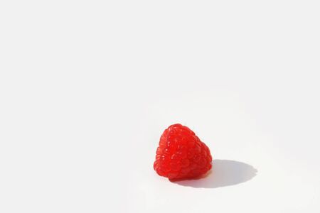 Single raspberry against white background