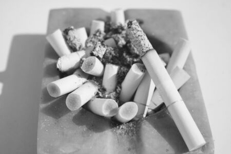 Close-up of square ashtray full of burnt cigarettesの写真素材