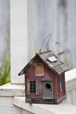 Country folk style bird house on front porch railingの写真素材