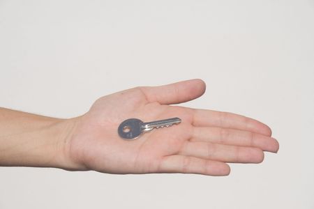 Extended hand with house key in palm against white backgroundの写真素材