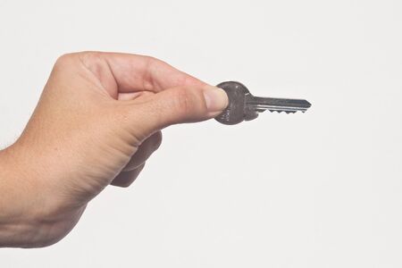Isolated hand reaching in with single key between fingersの写真素材