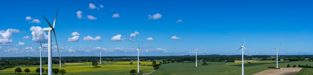 Panoramic aerial view and closeup of a wind turbine in a wind farm with rape field
