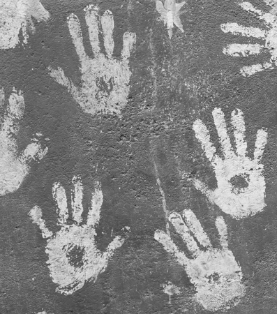 White paint handprints on a grey wall
