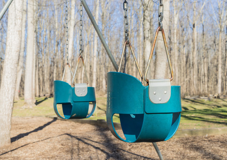 Old and rusty swings at the park's kids playground.の写真素材