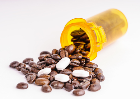 Coffee with big white pills spilling from the pill box - coffee as medication conceptの写真素材