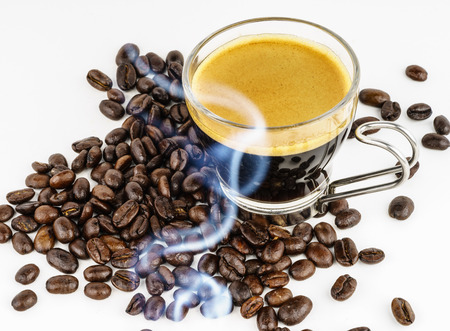 Small glass cup of coffee with coffee beans and smokeの写真素材