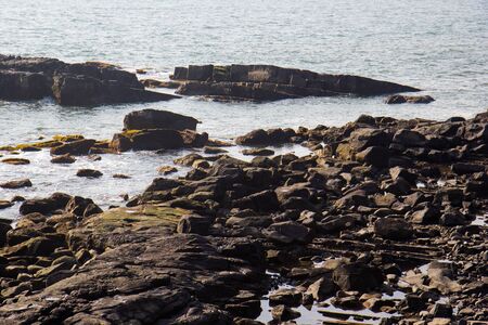 Waves break on the rocky beaches of Arambol in India.の写真素材