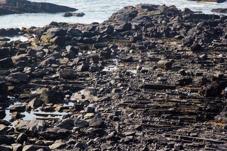 Waves break on the rocky beaches of Arambol in India.の写真素材