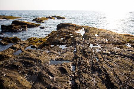 Waves break on the rocky beaches of Arambol in India.の写真素材