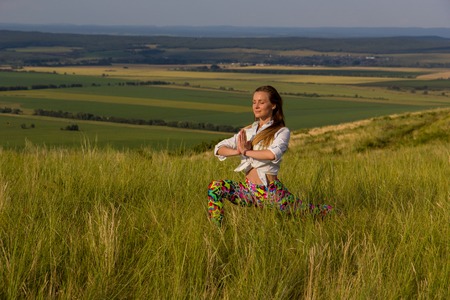 Young girl doing yoga fitness exercise outdoor in beautiful mountains landscape. Shikhan mountain Tra-Tau, Toratau. Alone mountain Russia, Bashkortostan, South Uralの写真素材