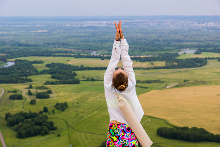 Young girl doing yoga fitness exercise outdoor in beautiful mountains landscape. Shikhan mountain Tra-Tau, Toratau. Alone mountain Russia, Bashkortostan, South Uralの写真素材