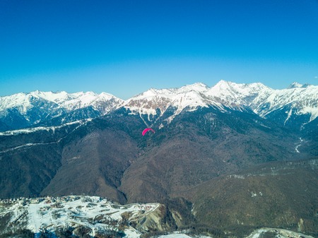 Paraglider flies over the mountains over the ski resortの写真素材