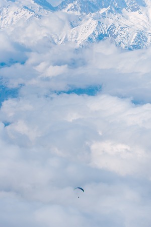 The paraglider flies over the clouds in the Caucasus Mountainsの写真素材