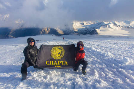 2014 07 Mount Elbrus, Russia: Mans holding the flag of Sparta on slope of Mount Elbrus