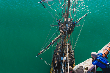 sailors work with sails at a height on a traditional sailboat in the sea