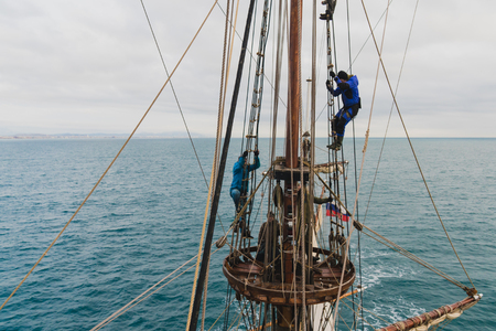 sailors work with sails at a height on a traditional sailboat in the seaの写真素材