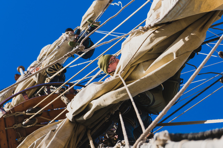 Sailors work with sails at a height on a traditional sailboatの写真素材