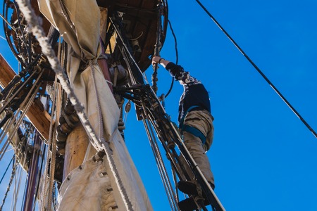 Sailors work with sails at a height on a traditional sailboatの写真素材